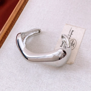 Detail of silver irregular streamlined open bangle with high polished finish on fabric