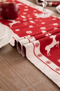 Detail of red Christmas table runner with knitted reindeer and snowflake patterns