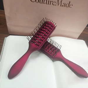 Dettaglio di due spazzole per capelli scheletro bordeaux opaco su un libro per acconciature