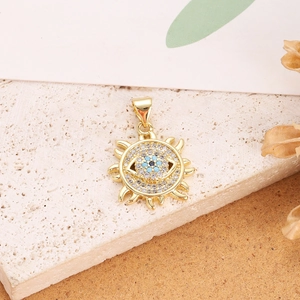 Macro shot of gold sun pendant with blue and white zircon evil eye on beige stone