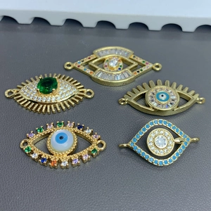 Macro shot of five golden evil eye pendants with sparkling zircons and green gemstones