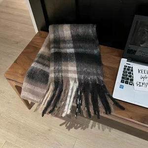 Detail view of plaid mohair scarf with tassels on wooden bench in cozy indoor setting