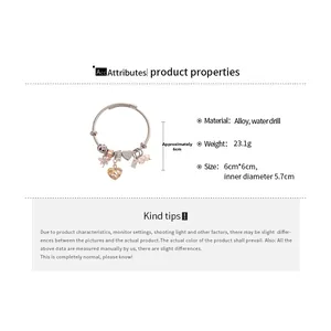 Detailed view of the rhinestone heart and flower charms on a rose gold plated bangle