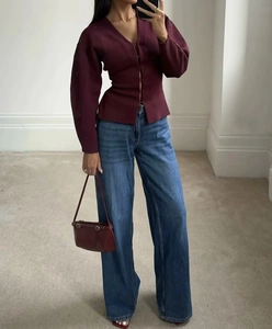 Détail d'un cardigan bordeaux en maille avec un jean large bleu et un sac à main