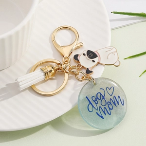 Close-up of golden keychain with dog mom resin pendant, white tassel and pug charm