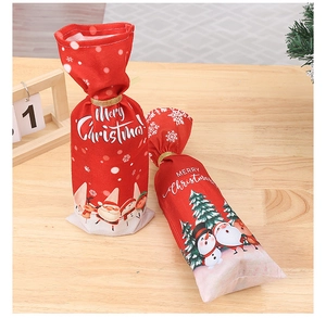 Detail of red Christmas wine bottle cover with Santa print on wooden table decoration