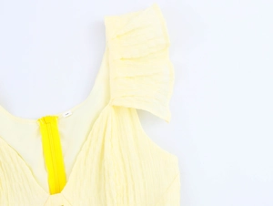 Detail view of light yellow textured dress featuring ruffle sleeves and back zipper closure