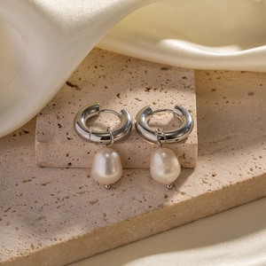 Detail view of silver hoop earrings with natural baroque pearl drops on stone
