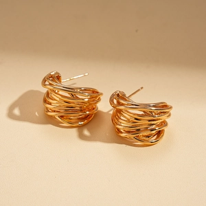 Detail view of multi-layer intertwined C-shaped gold-plated earrings with layered texture