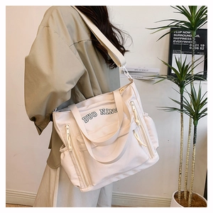 Lifestyle view of a large cream canvas tote bag with functional pockets and wide strap