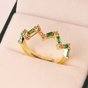 Detail of adjustable gold ring with emerald green stones and pavé crystals on velvet