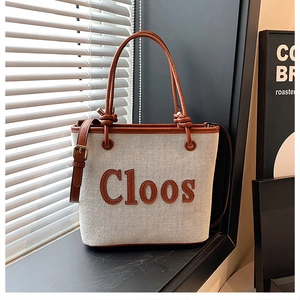 Detail of canvas tote bag with brown handles and leather trim featuring Cloos logo