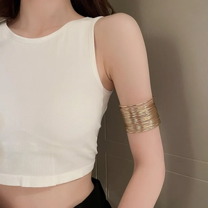 Close-up of layered golden upper arm cuff bracelet on a model against a neutral background