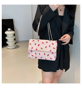 Détail du sac à bandoulière en velours côtelé rose avec imprimés fraises et chaîne dorée