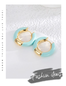 Detailed close-up of gold-plated hoop earrings with light blue enamel finish