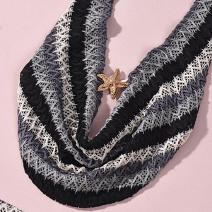 Detail of knit crop top with wave patterns and a golden starfish pendant ornament