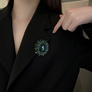 Detail of vintage emerald crystal flower brooch pinned on a black blazer lapel