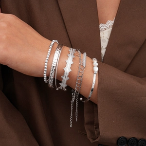 Detail of seven-piece silver-tone bracelet set with rhinestones on a blazer background
