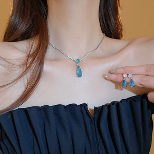 Close-up of elegant water drop jewelry set with blue zircon crystals on female model