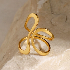 Artistic golden stainless steel ring displayed on a natural textured stone surface