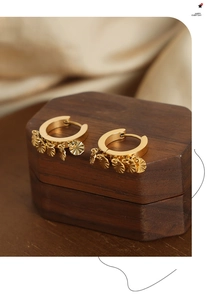 Gros plan de boucles d'oreilles dorées en U avec pendentifs rayés sur un coffret cadeau