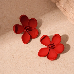 Macro shot of matte red flower earrings with 3D petals on a beige stone base