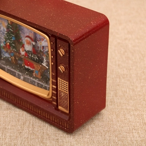 Close-up of vintage red TV snow globe with Santa Claus and sparkling glitter detail