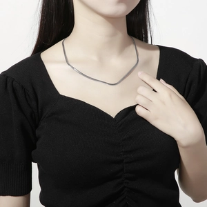 Detailed close-up of a silver herringbone snake chain necklace on a female model