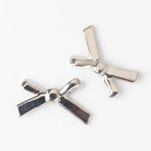 Close-up of two silver bow-shaped metal alloy beads for DIY jewelry making and crafts