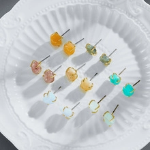 Macro view of colorful irregular raw gemstone stud earrings with gold claw settings