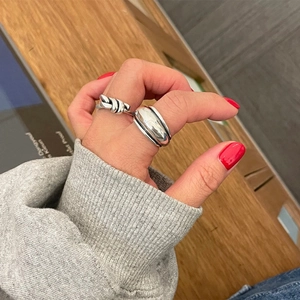 Silver 925 knot and wide band ring set worn against a grey knit sleeve background