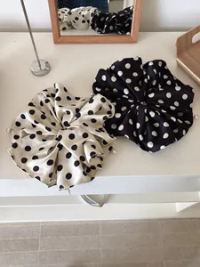 Close-up of oversized satin polka dot hair scrunchies with white pearl bead accents