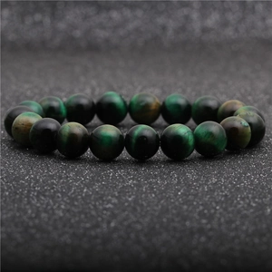 Detailed view of green tiger eye beaded bracelet with natural silky luster on dark texture