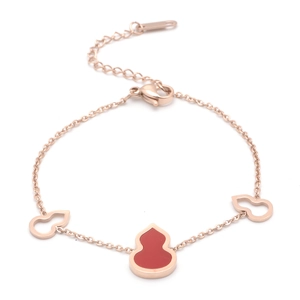 Detail of rose gold stainless steel bracelet with red shell gourd charms and clasp