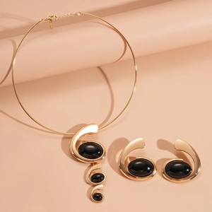 Golden geometric resin choker and earrings set with oval black stones on pink background