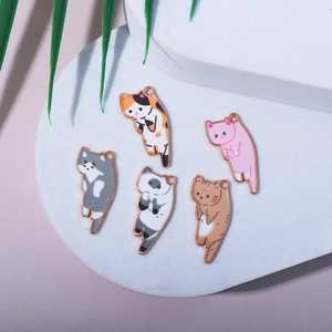 Flat lay of five cartoon cat enamel charms in various colors on a white plate