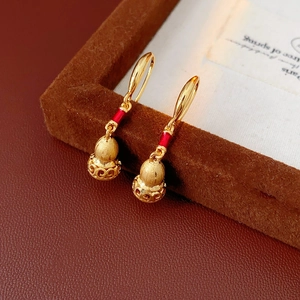 Detailed close-up of matte gold gourd earring with red inlay and hollow cloud patterns