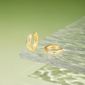 Macro shot of gold silver huggie hoop earrings with micro-paved white zircons