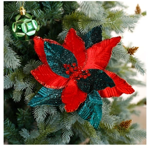 Close-up of red and dark green velvet Christmas flower with gold glitter on tree