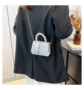 Silver glitter flap bag with pearl handle shown on model in black suit jacket