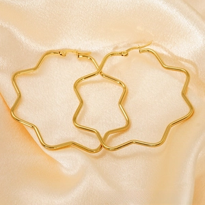 Macro shot of large gold-plated irregular star earrings on soft champagne silk fabric