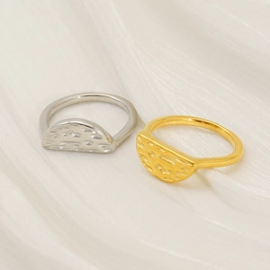 Detail of silver and gold rings with hammered texture design on white fabric