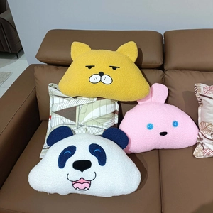 Plush cartoon animal pillows featuring cat rabbit and panda designs on a leather sofa