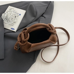 Dettaglio di una borsa a nuvola marrone plissettata con manico tondo e texture in pelle