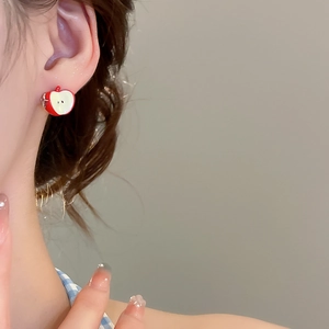 Detail shot of red apple slice earrings with silver needles worn on model's ear