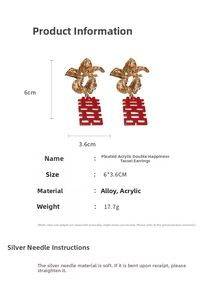Macro view of Chinese wedding earrings with red acrylic Xi character and gold metal