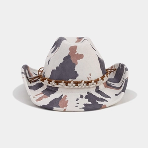 Detail of western cow print felt hat featuring an ethnic woven band and side tassel charm