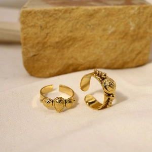 Detail of vintage gold-plated open rings with ornate ethnic textures on beige fabric