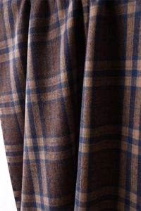 Close-up of thick plaid cashmere-like fabric showing brown and navy blue woven texture