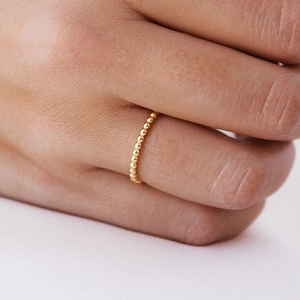 Minimalist 18k gold beaded ring featuring continuous round balls for women on a white background